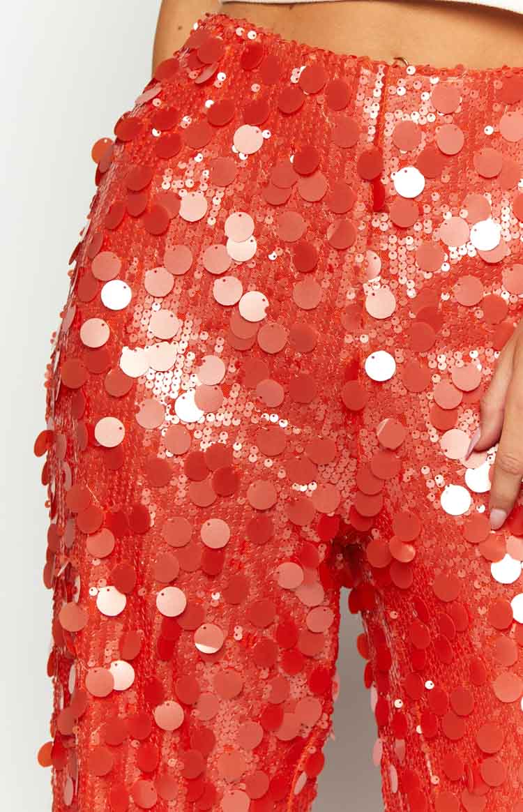 Close-up of the vibrant orange sequin pants showing large reflective round sequins