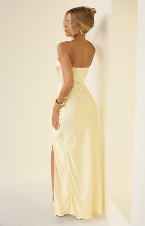 Side view of a yellow strapless satin maxi dress with ruched detailing on the hip and a high side slit
