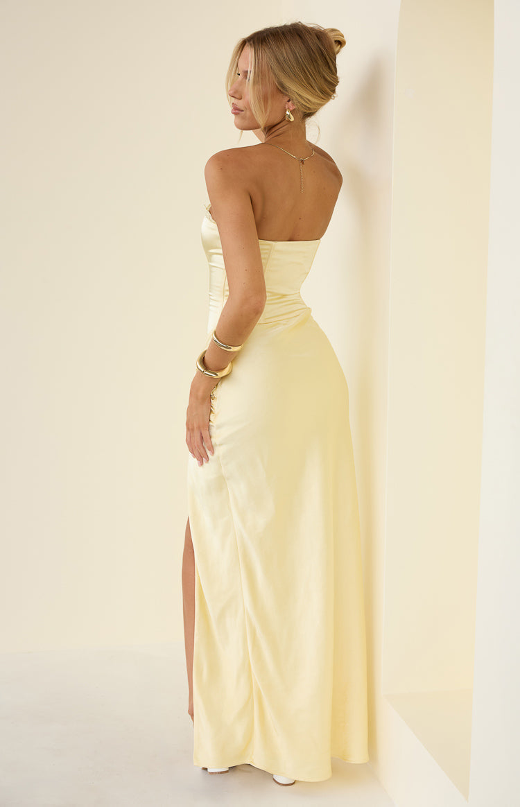 Side view of a yellow strapless satin maxi dress with ruched detailing on the hip and a high side slit