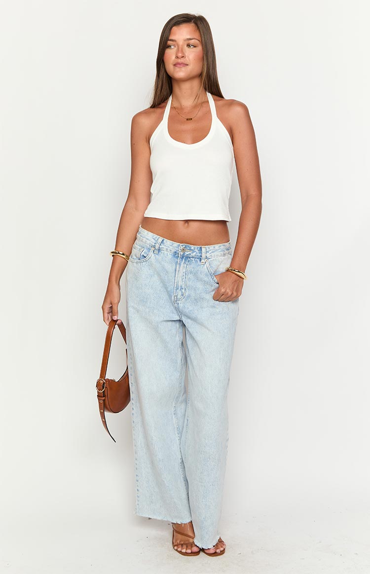 Full-length front view of a white ribbed knit cropped halter neck top with a scoop front