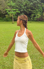 Side view of a white ribbed knit cropped halter neck top with a V-neckline