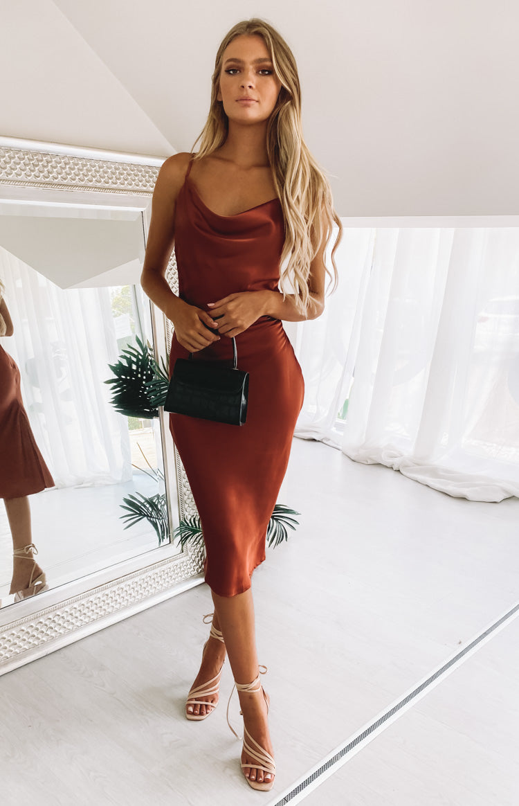 Rust satin midi dress with a cowl neckline and thin straps, featuring a sleek silhouette for a formal event