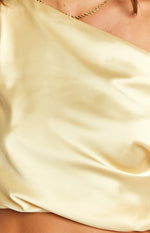 Close-up of the smooth, lustrous yellow satin fabric of the crop top, showing its soft drape and subtle sheen