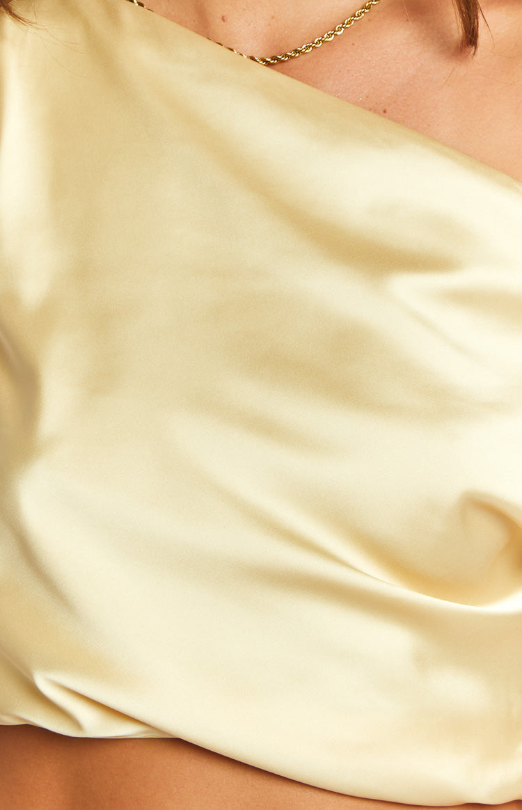 Close-up of the smooth, lustrous yellow satin fabric of the crop top, showing its soft drape and subtle sheen