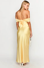 Rear view of a yellow off-shoulder maxi dress with a large tie-back detail and flowing satin fabric