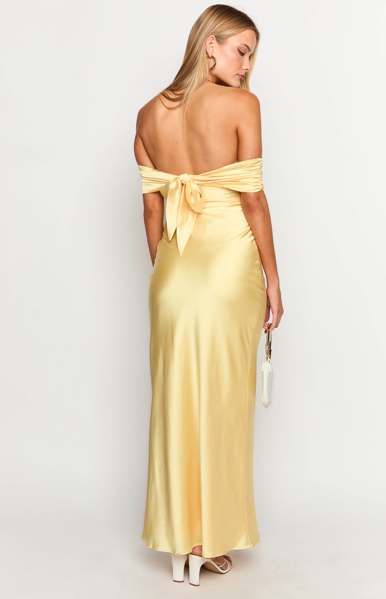 Rear view of a yellow off-shoulder maxi dress with a large tie-back detail and flowing satin fabric