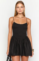 Brunette model wearing a black ini dress with a shirred bust and flared skirt