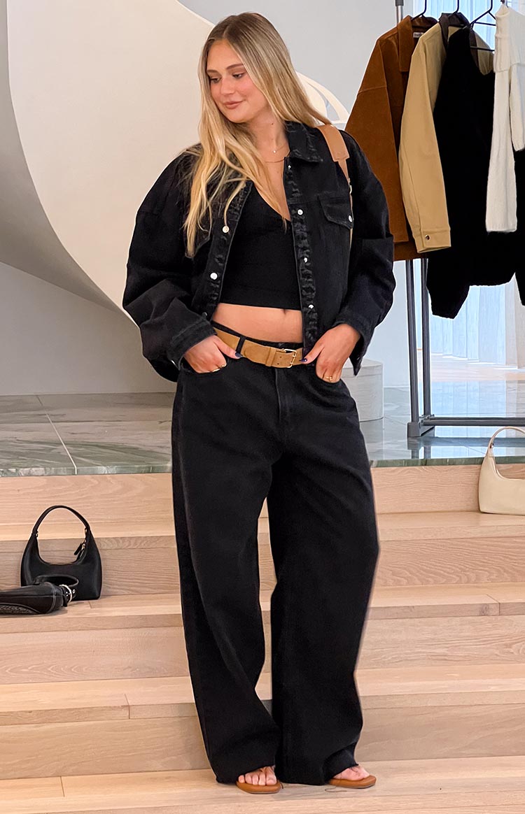 Full length view of black wide leg boyfriend jeans with a relaxed fit and a tan belt