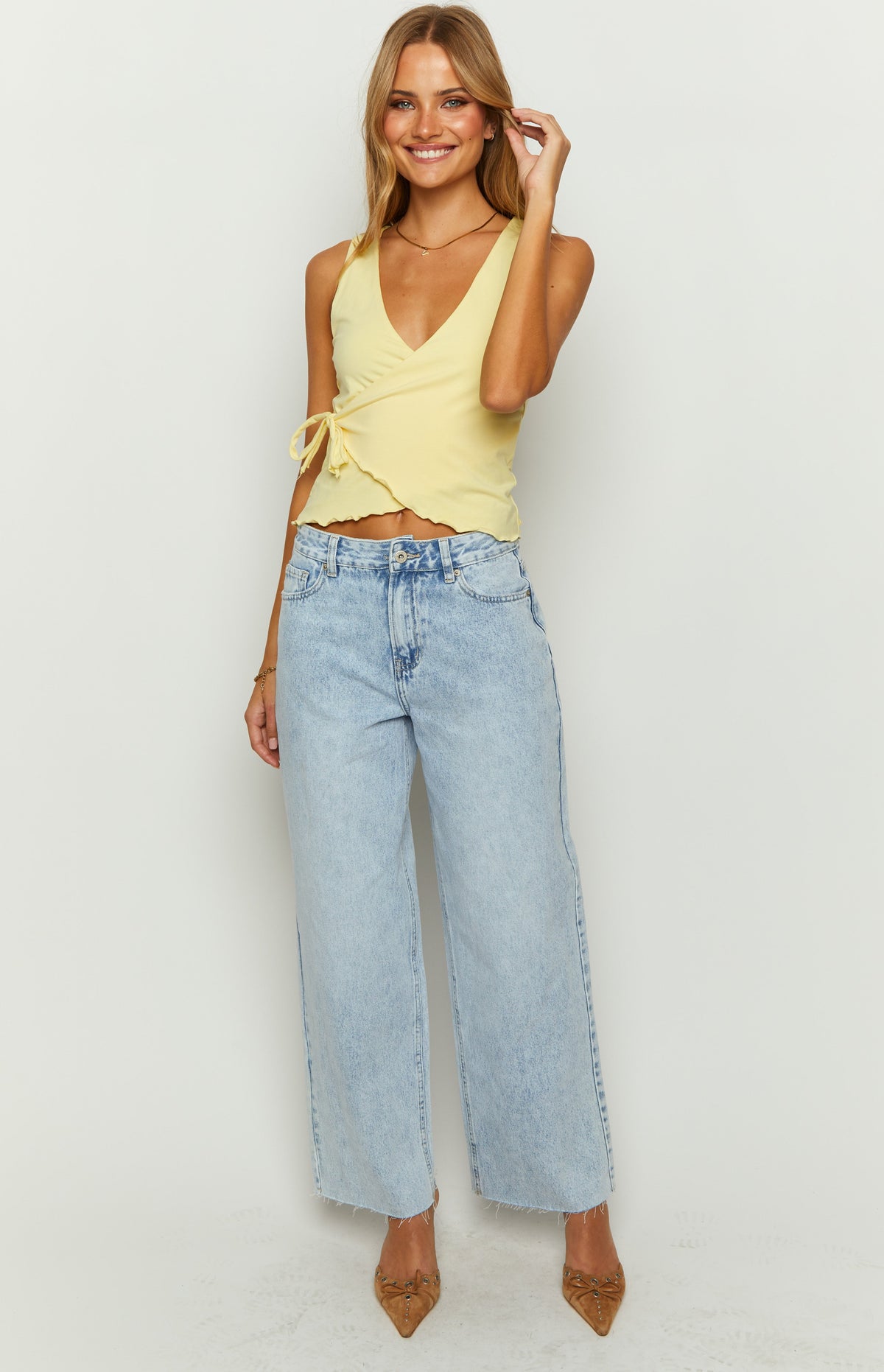 Front view of light wash denim wide leg boyfriend jeans with a high waist and raw frayed hem