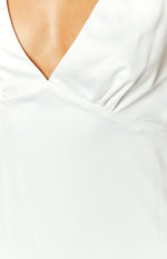 Close-up of the white satin V-neckline and gathered bust detail of the mini dress