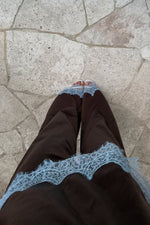 Top-down view of a brown satin top featuring wide light blue lace trim along the bottom hem