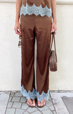 Full length view of brown satin wide-leg pants with light blue scalloped lace trim at the hem