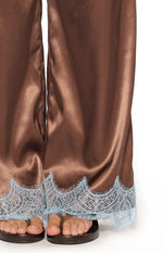 Close-up of the light blue scalloped lace trim at the hem of the brown satin wide-leg pants