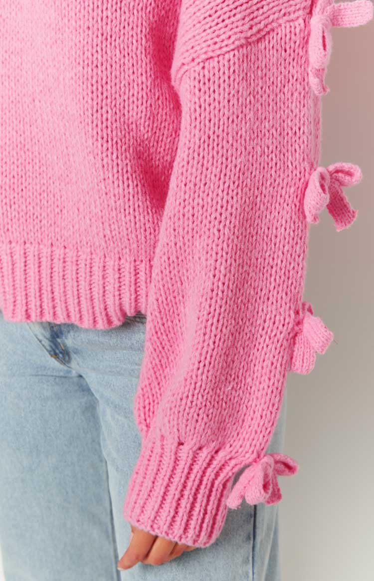 Close-up of the pink knit jumper sleeve with multiple bow details and a wide ribbed cuff