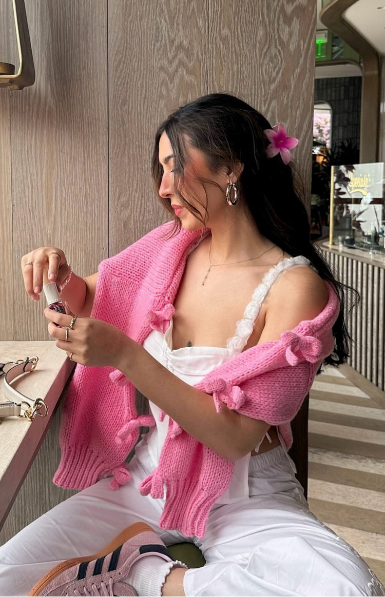 Close-up of the chunky pink knit jumper with a mock neck and bow details on the sleeves