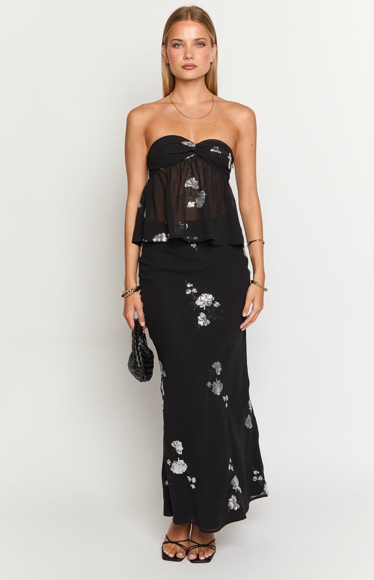 Front view of a black maxi skirt with a scattered silver floral print and a flowing silhouette