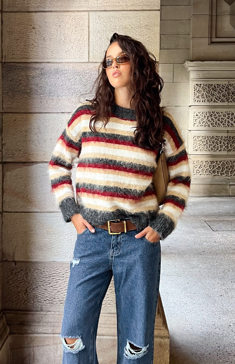 Front view of an oversized multi-stripe fuzzy sweater with dark grey, white, beige, and red stripes, ribbed cuffs and hem
