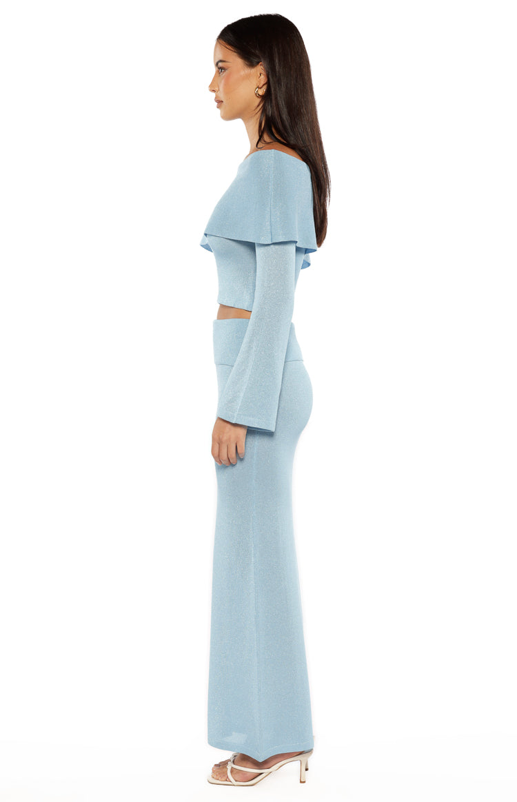 Side view of the blue shimmery knit off-shoulder top with a flounce neckline and long flared sleeves
