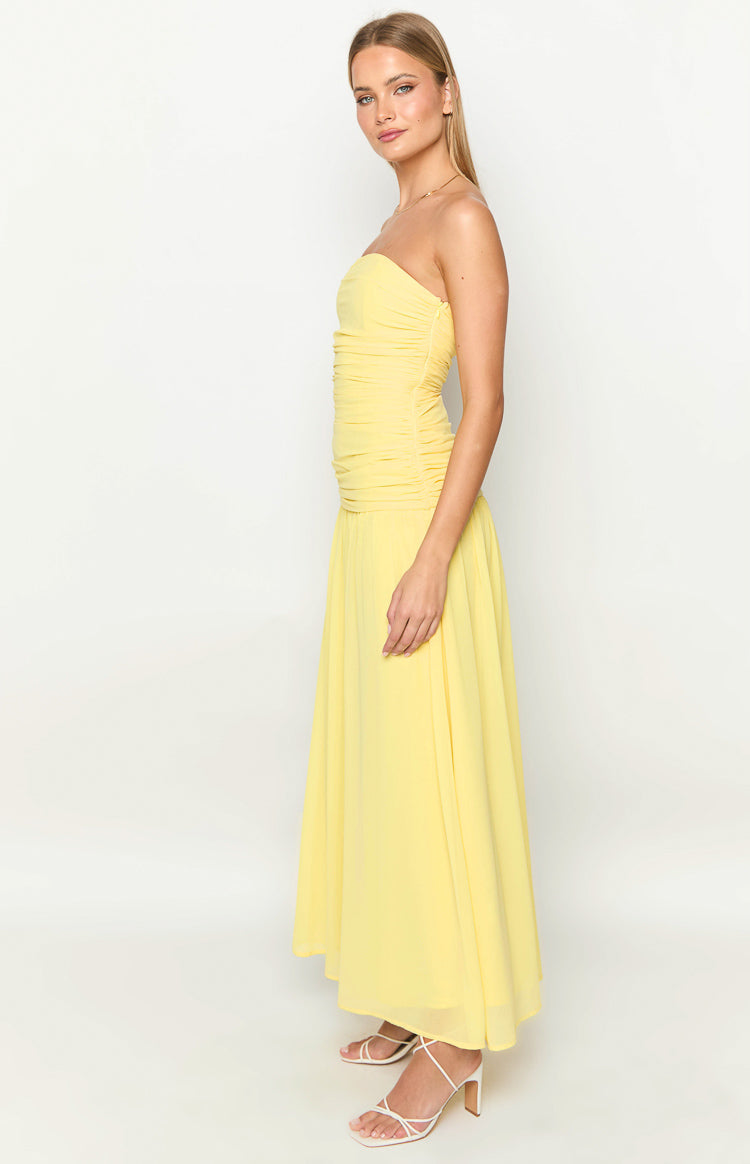 Side view of a yellow strapless maxi dress with a ruched bodice and a flowing skirt