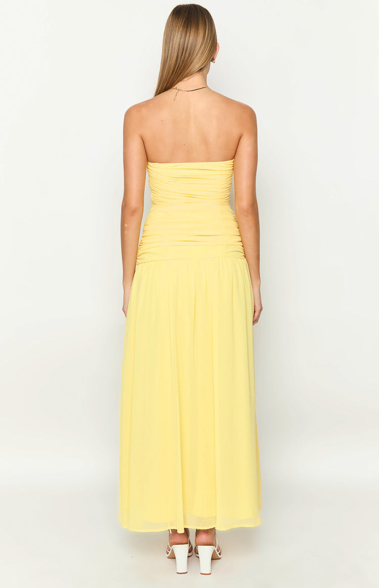 Rear view of a yellow strapless maxi dress with a ruched bodice and a flowy pleated skirt