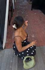 Top-down view of a black satin spot maxi dress with a sweetheart neckline and thin spaghetti straps