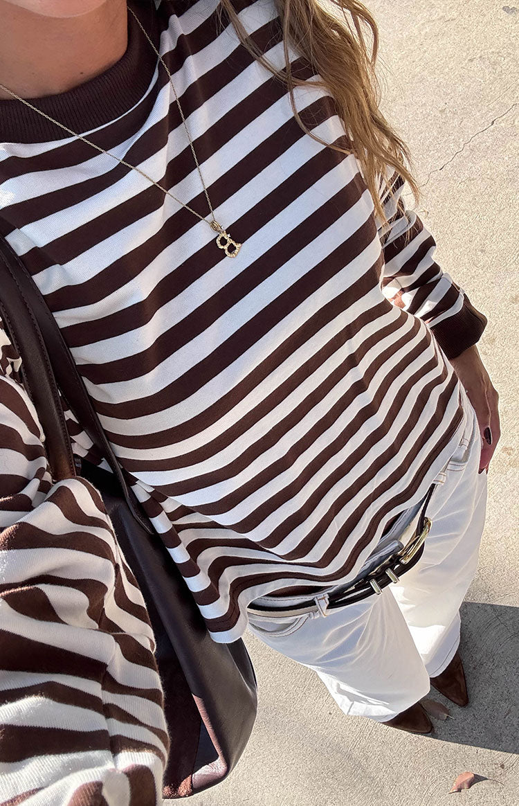 Overhead view of a chocolate and white striped long sleeve top, showing the relaxed fit and ribbed cuffs