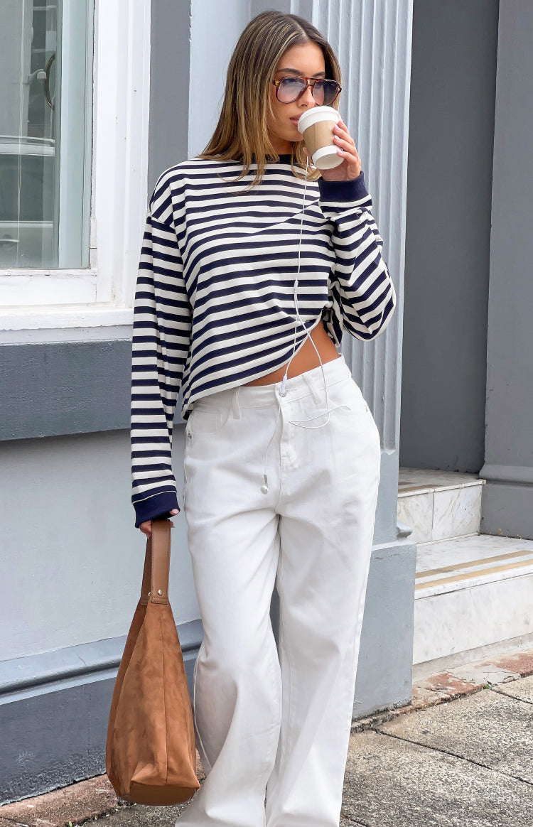 Side view of a navy and white striped long sleeve top with a relaxed fit and cropped hem