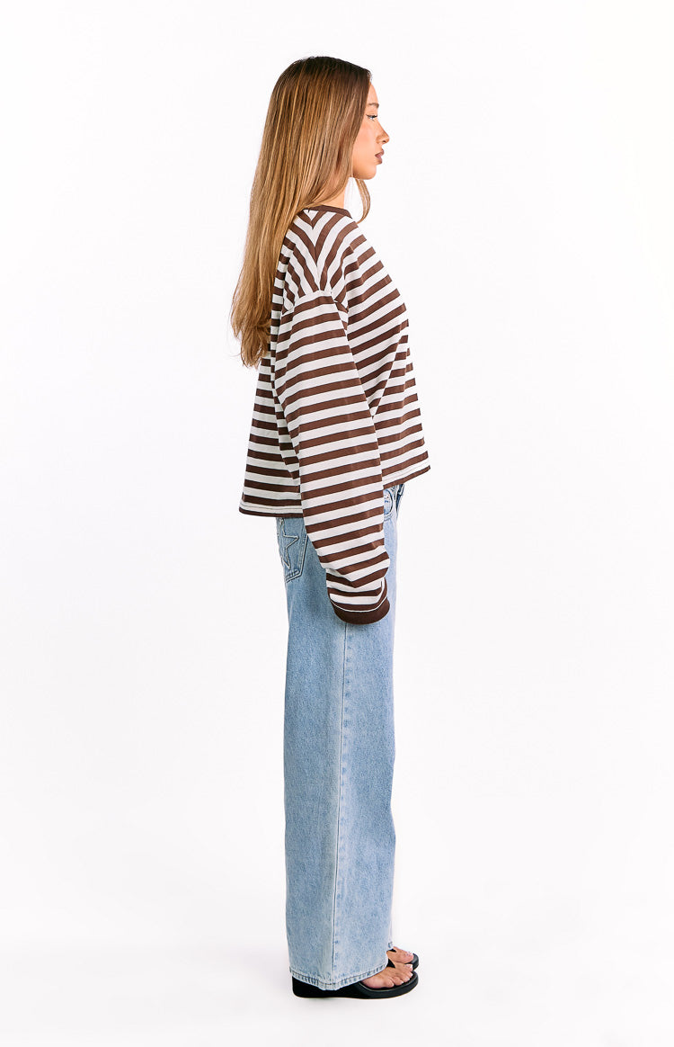 Side view of a chocolate and white striped long sleeve top with a relaxed fit and dropped shoulders
