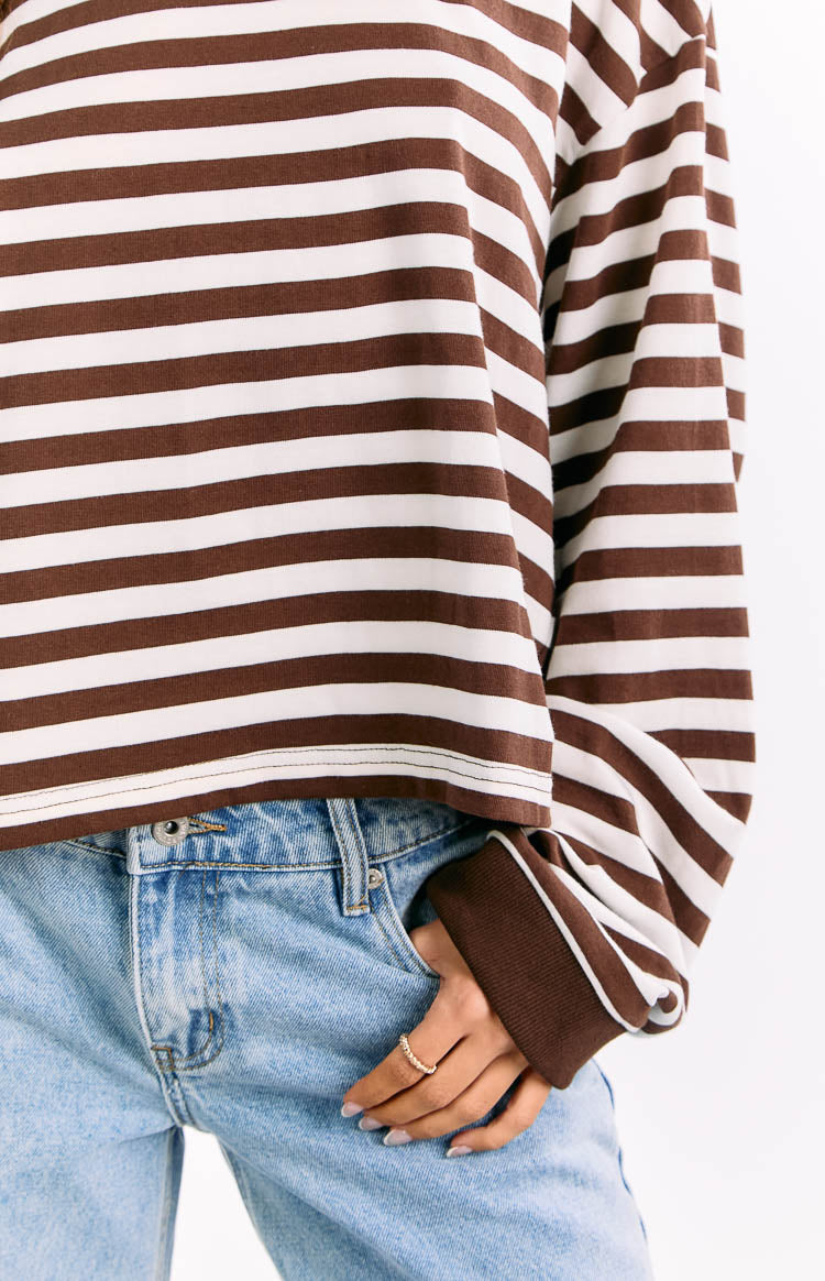 Close-up of the straight cropped hem and ribbed cuff with white trim on a chocolate and white striped long sleeve top