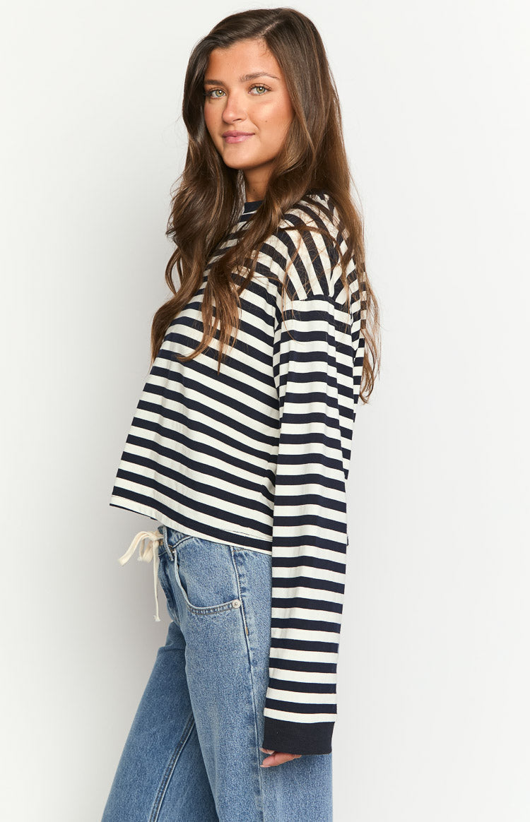 Side view of a navy and white striped long sleeve top with a cropped hem and white drawstring detail
