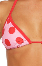 Close-up of the pink and red polka dot triangle bikini top with red contrast binding and gathered bottom edge