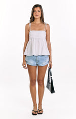 White ruched tie strap top with a square neckline and a flowy peplum hem
