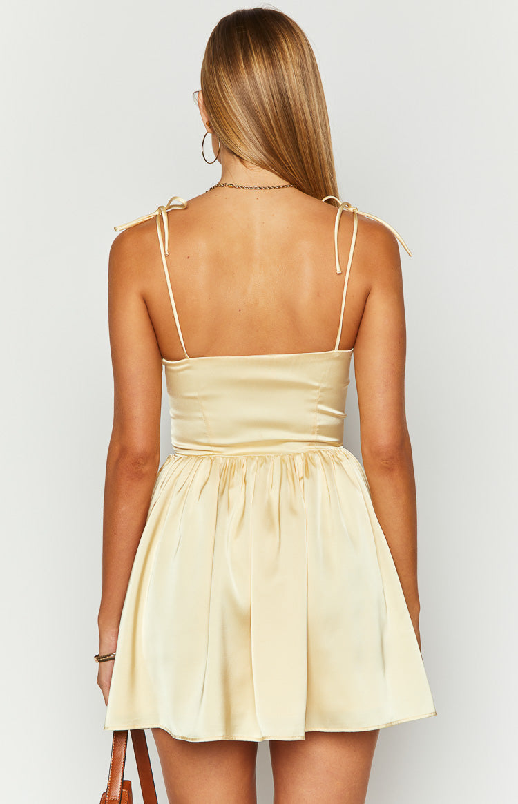 Rear view of a yellow mini dress with tie-shoulder spaghetti straps, fitted bodice, and gathered flowy skirt