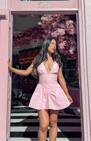 Pink micro mini dress with a deep V-neckline, fitted bodice, and gathered voluminous skirt
