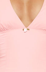 Close-up of the V-neckline with a small white rose applique and gathered detail on a pink mini dress