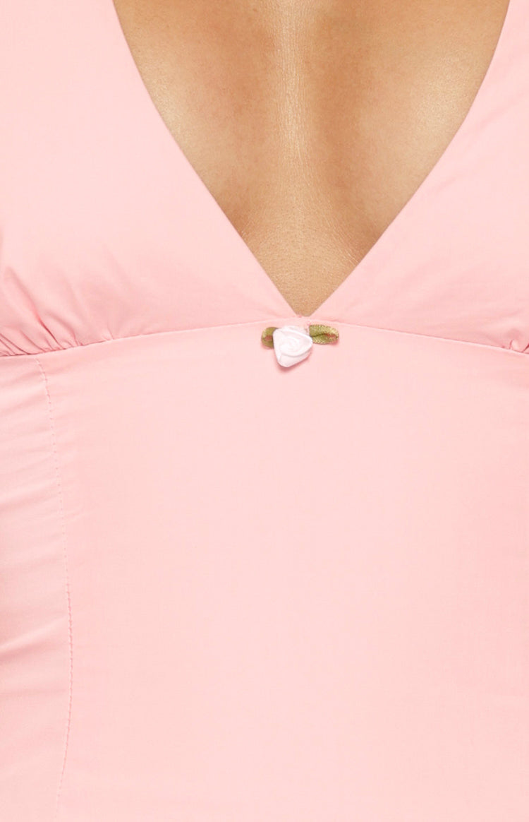 Close-up of the V-neckline with a small white rose applique and gathered detail on a pink mini dress