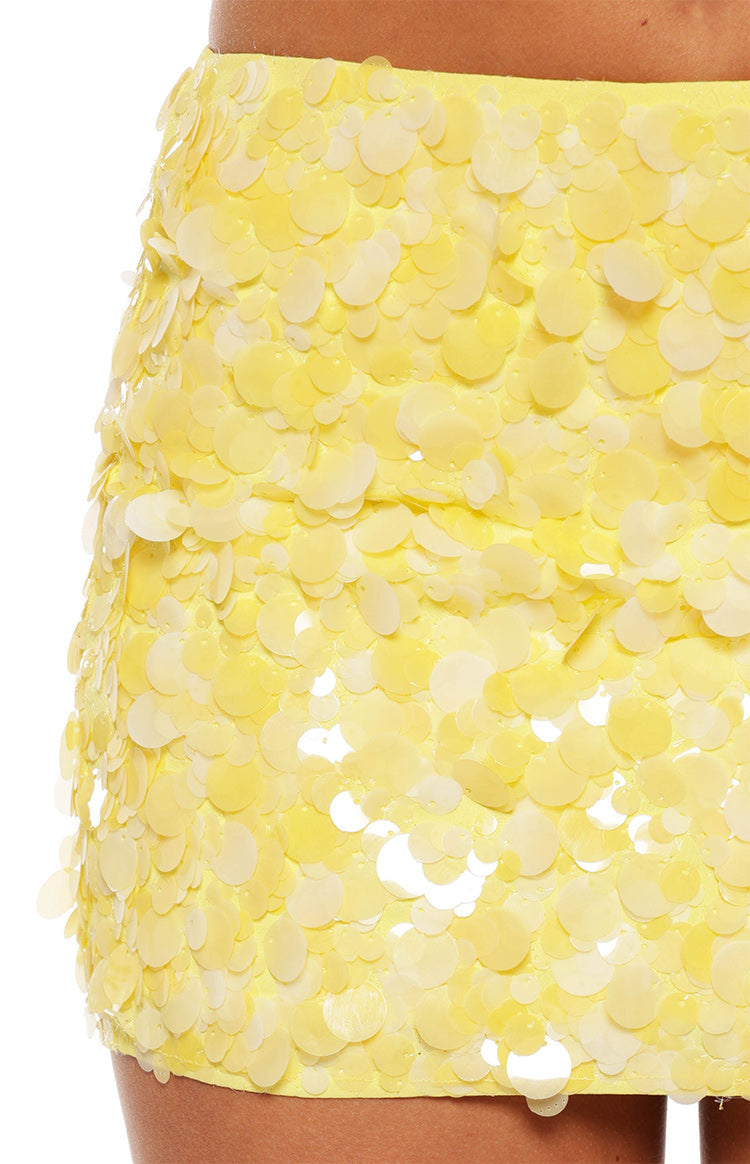 A close-up of a mini-skirt completely covered in large overlapping pale yellow and off-white sequins.