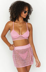Close-up of a pink sparkle mini skirt with a sheer open-knit texture and a high side slit