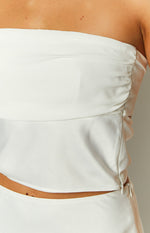 Close-up of the side of a white satin crop top, showing ruched detail and the invisible zipper