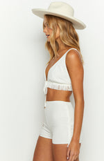 Side view of white fitted mini shorts with fringe detail along the outer seam