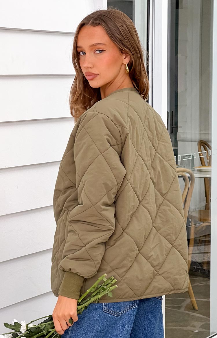 Back view of a khaki quilted bomber jacket with diamond pattern and ribbed cuffs