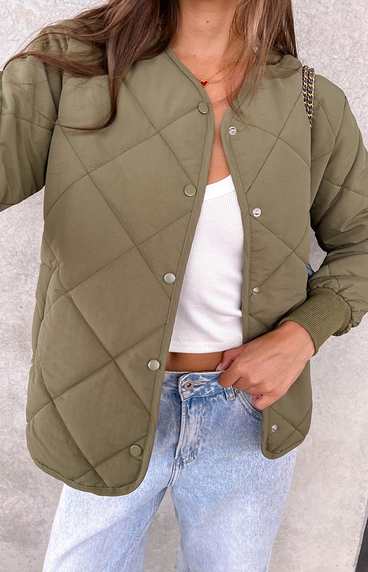 Close-up of the khaki quilted bomber jacket with snap button closure, collarless V-neck, and ribbed cuffs