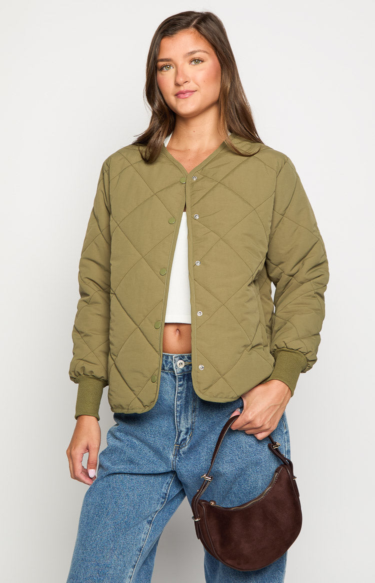 Front view of a khaki quilted bomber jacket, unbuttoned to show the V-neckline, snap button closure, and ribbed cuffs