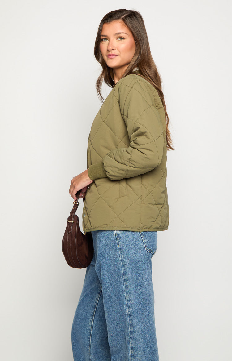 Side view of a khaki quilted bomber jacket with ribbed cuffs and a relaxed fit