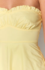 Close-up of the ruffled strapless neckline and gathered bust detail of a yellow mini dress