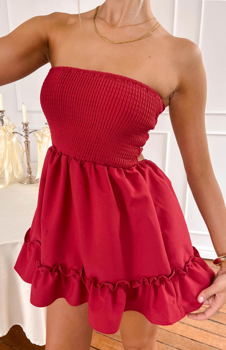 Close-up of the red strapless smocked bodice, side waist cutout, and flowy skirt with ruffled hem