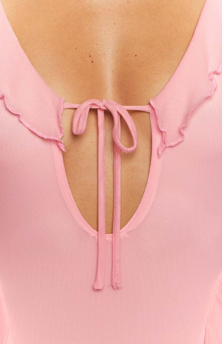 Side view of a pink mesh long sleeve mini dress, highlighting the sheer sleeves and ruffled trim details