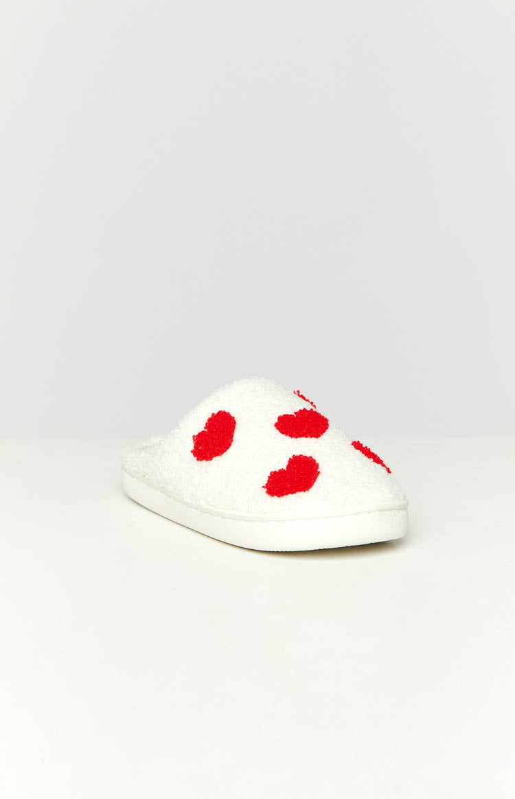 Side view of a white fluffy slipper with red heart patterns and a thick white rubber sole