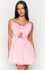 Front view of a light pink strapless mini dress with a large bow detail on the bust and a cutout under the bust
