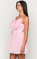 Side view of a pink strapless mini dress with a large bow on the bust and a full, layered tulle skirt, showing the side zipper